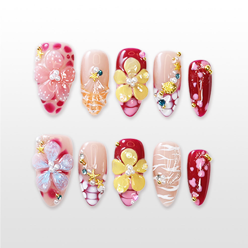 Colorful floral press-on nails with red, nude, and pink base, pearl and rhinestone details