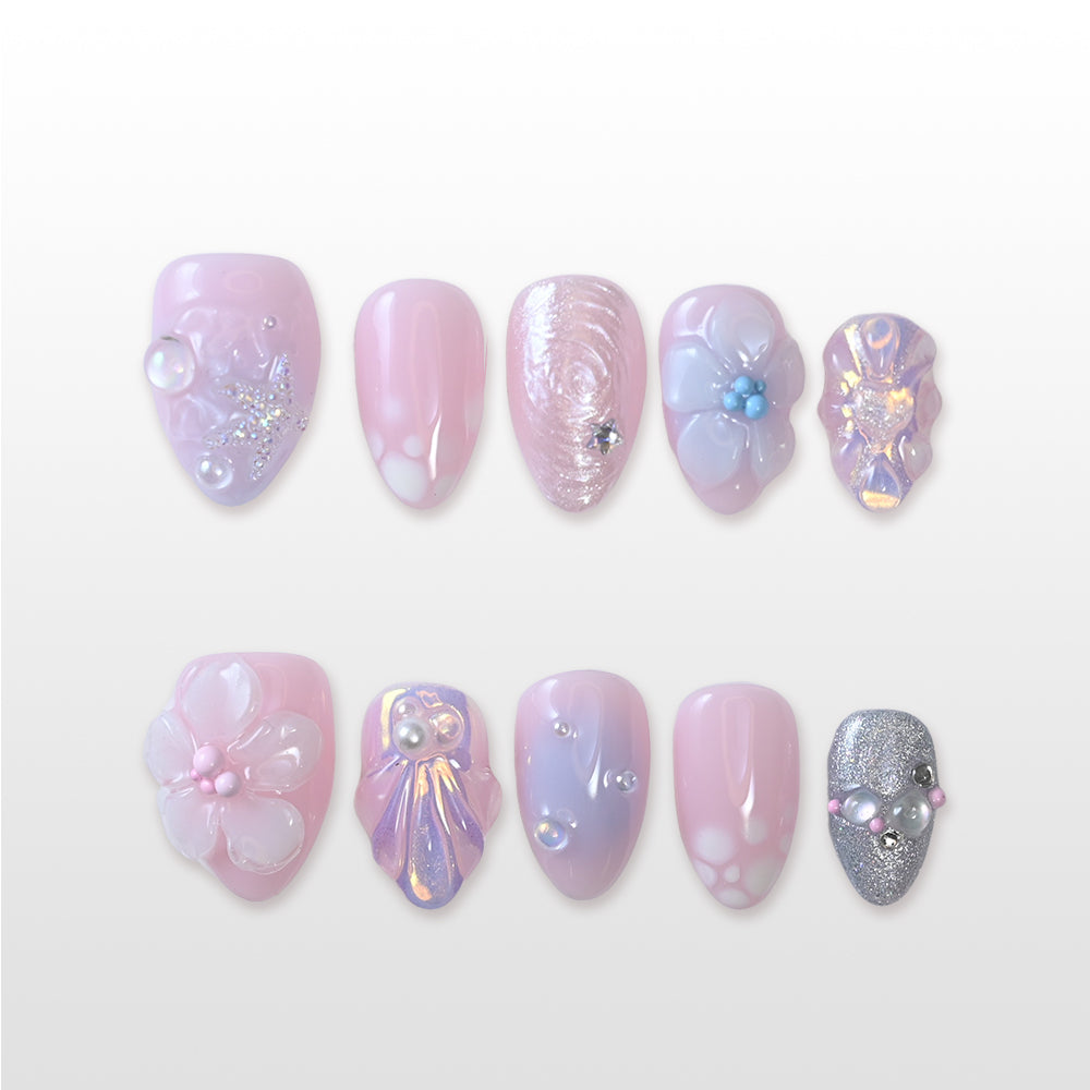 Pink and lavender press-on nails with pearls, glitter, and seashell accents