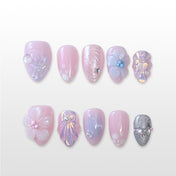 Pink and lavender press-on nails with pearls, glitter, and seashell accents