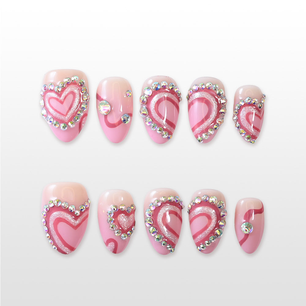 Pink heart-shaped press-on nails with rhinestone borders and glitter accents