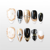 Luxury black and gold press-on nails with rhinestone cross and textured details