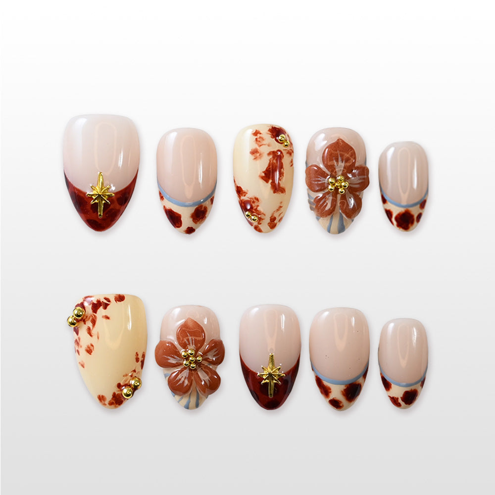 Handmade brown marble nails featuring gold embellishments, floral accent, and blue stripe detail