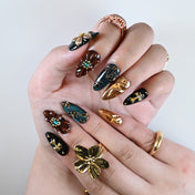  Reusable press on nail set with gold swirl texture, vintage flower design, and black glossy base