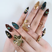 Hand model wearing opulent press on nails styled with rings, perfect for holiday or winter looks