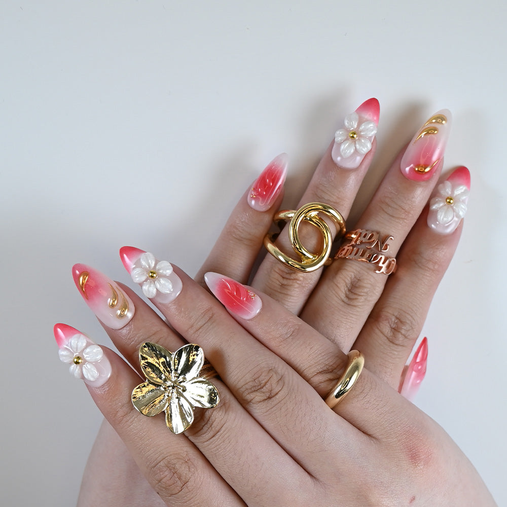  Elegant press on nails with white blossoms, coral pink base, and metallic design details