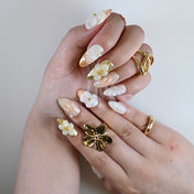 Cream and nude 3D floral press on nails with gold accents worn with matching rings