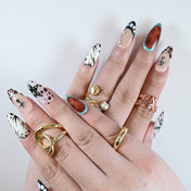 Medium almond-shaped press on nails styled with layered gold rings and bold motif mix