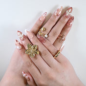 Almond-shaped press on nails styled with gold jewelry and dreamy pink star designs