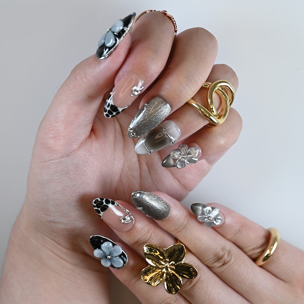 Luxury mixed media press on manicure worn with gold rings and artistic nail textures