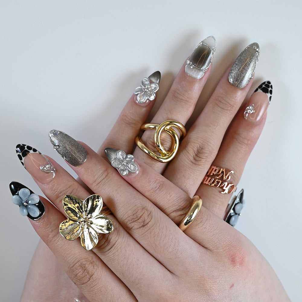 Creative nail design with black French tips, metallic gradients, and 3D acrylic flowers