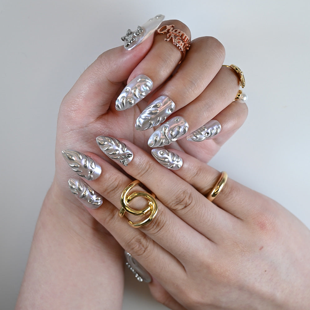 Hand photo showing holographic silver press on nails with crystal details and fluid design