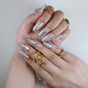 Hand photo showing holographic silver press on nails with crystal details and fluid design