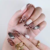 Rose gold chrome press on nails worn on hand with statement rings