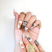 Handmade almond nails with pink flowers, metallic gold designs, and abstract patterns