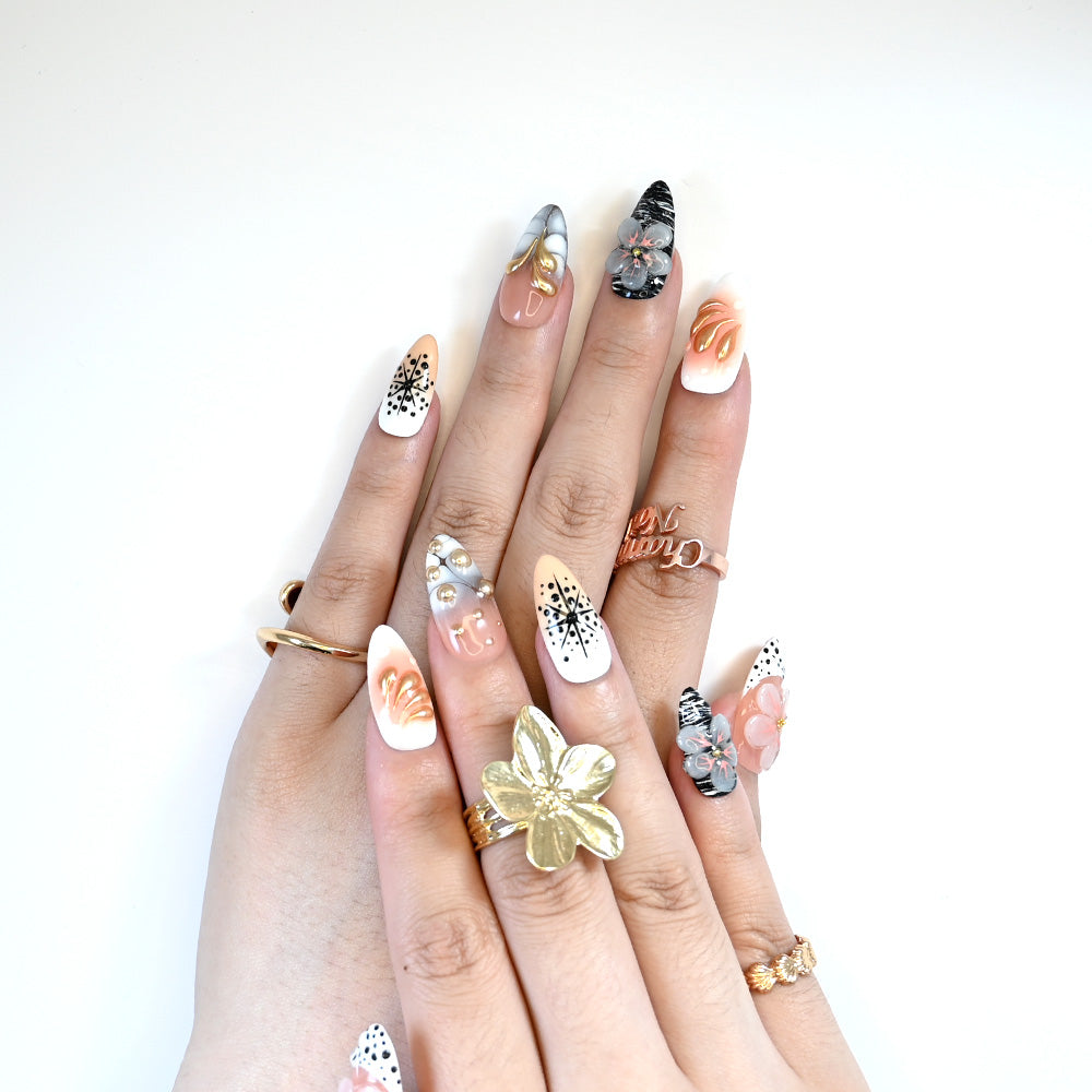 Elegant nude nails with 3D flowers, gold drop art, and modern black line details