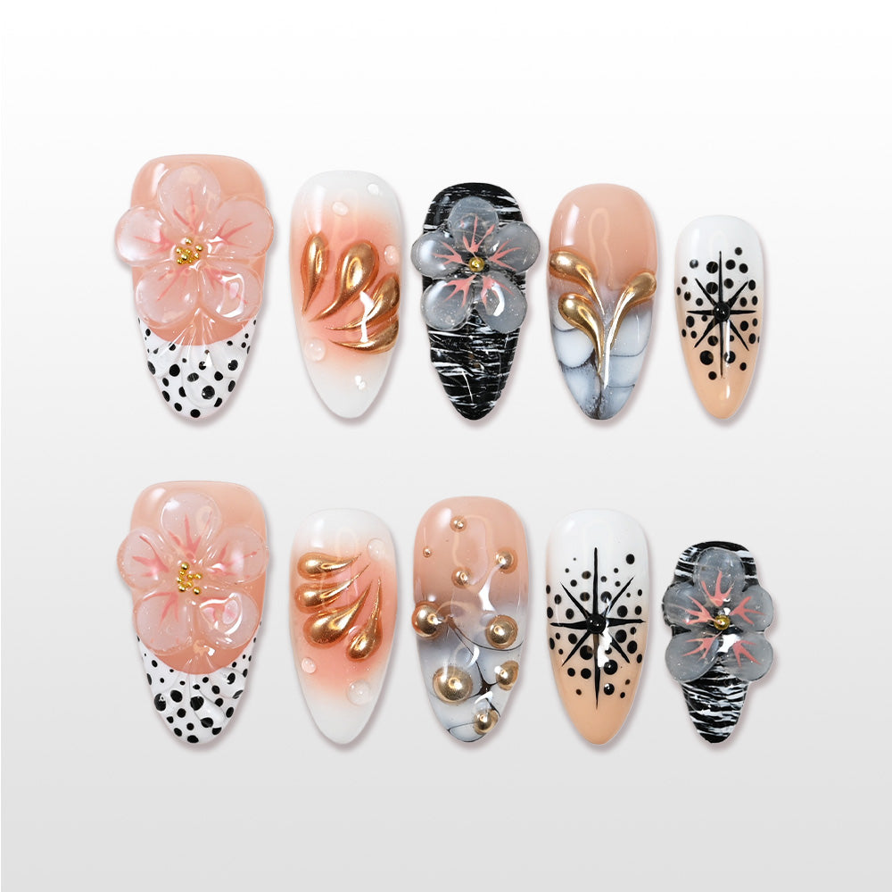 Nude and white press-on nails with 3D floral accents, gold petals, and black polka dots