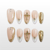 Medium almond press-on nails with nude base, gold cross charms, and starburst accents