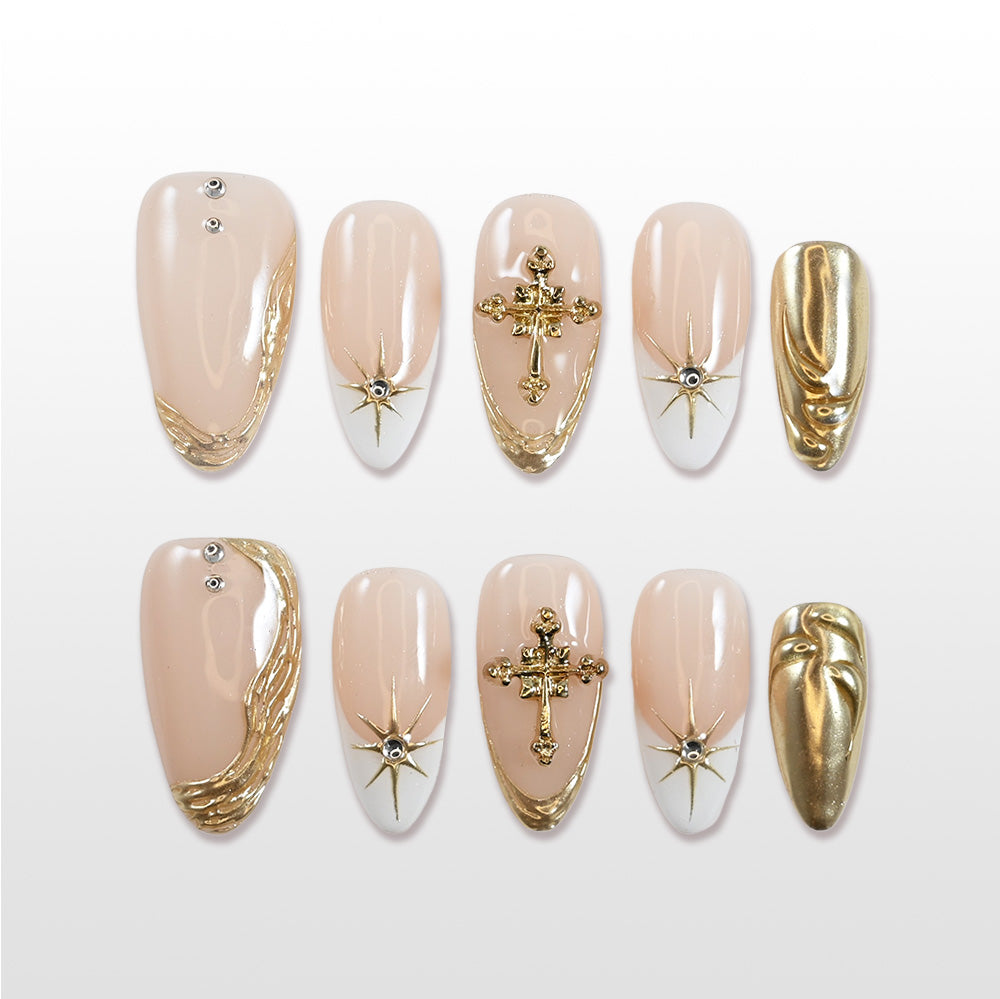 Medium almond press-on nails with nude base, gold cross charms, and starburst accents