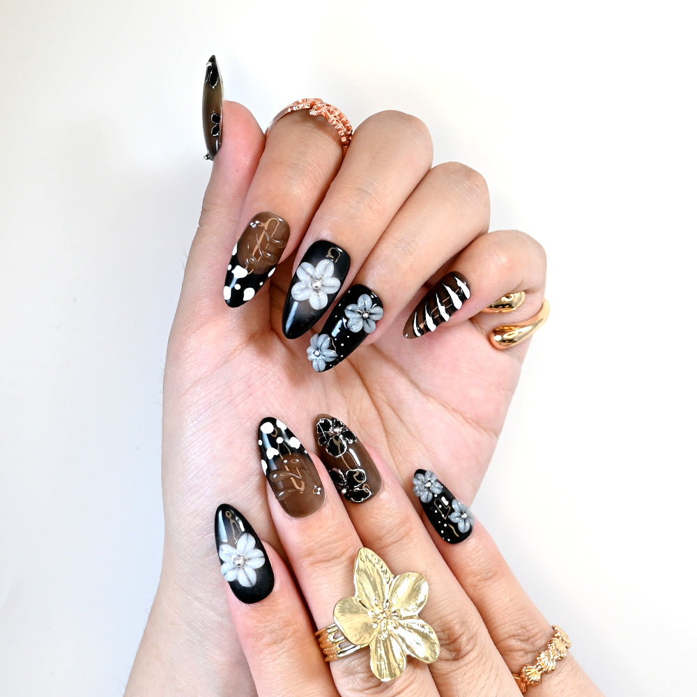 Handmade press-on nails with metallic gold, monochrome floral patterns, and stripe details