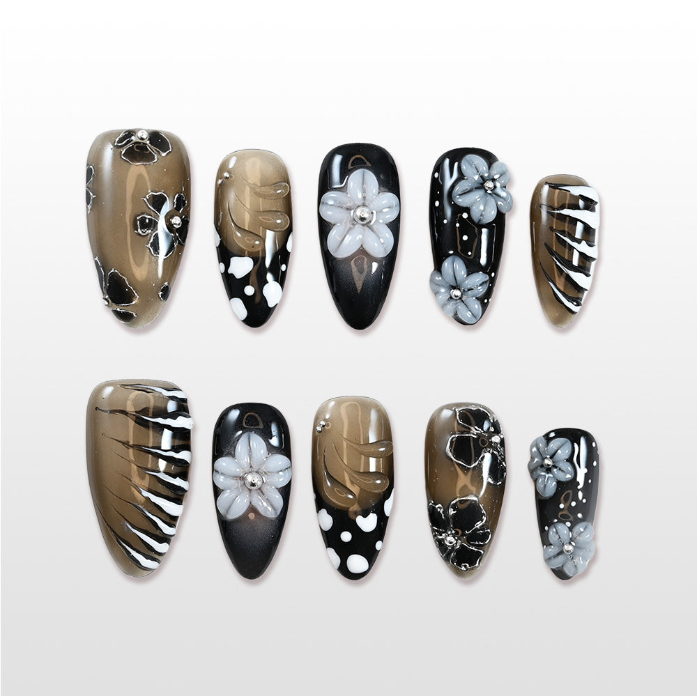 Medium almond press-on nails with black, gold, and grey 3D flowers, rhinestones, and polka dot accents