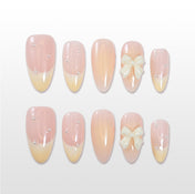 Pastel pink and yellow gradient press-on nails with 3D bow accent and pearl details
