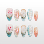 Pearl finish press-on nails with blue gradient tips, 3D floral designs, and gold accents
