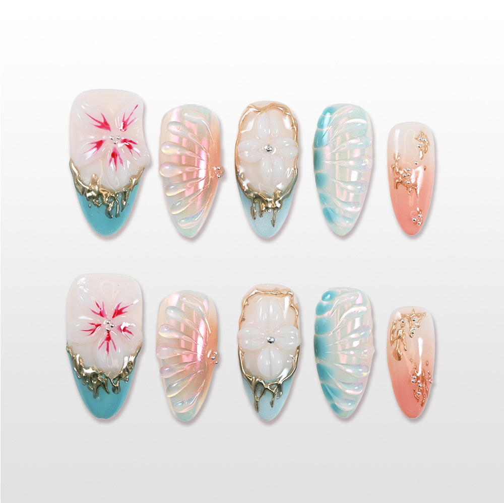 Pearl finish press-on nails with blue gradient tips, 3D floral designs, and gold accents