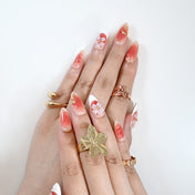 Romantic press-on nails with coral pink fade, flower embellishments, and glossy finish