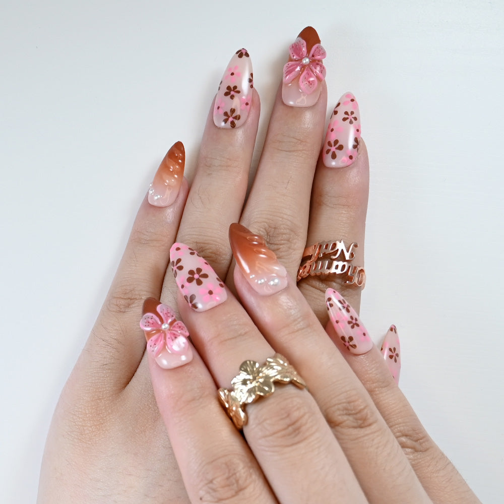 Handmade press-on nails with pink flower design and chocolate accents