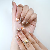Handmade acrylic nails featuring caramel brown tones, flowers, and chrome details