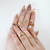 Elegant flower design press-on nails in brown nude shades with metallic charm