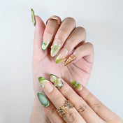Handmade almond nails with emerald green, nude base, and floral design