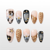 Black and gold press-on nails with 3D white floral accents