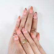 Elegant almond nails with peach gradient, 3D petals, and gold details