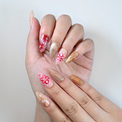 Medium almond reusable press-on nails with glossy red accents and gold shimmer