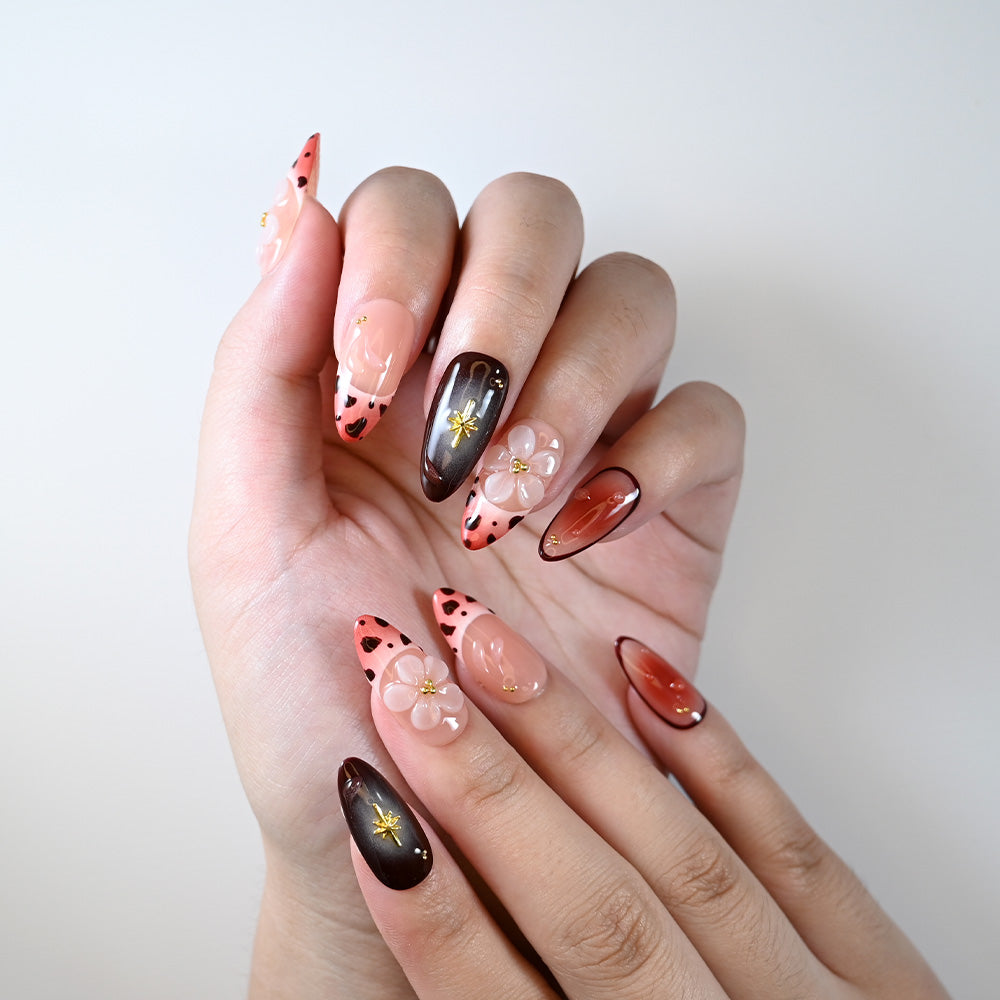 Medium almond reusable press-on nails with gradient pink tips and floral accents