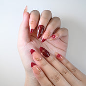 Medium almond reusable press-on nails with burgundy red tips and gold foil details