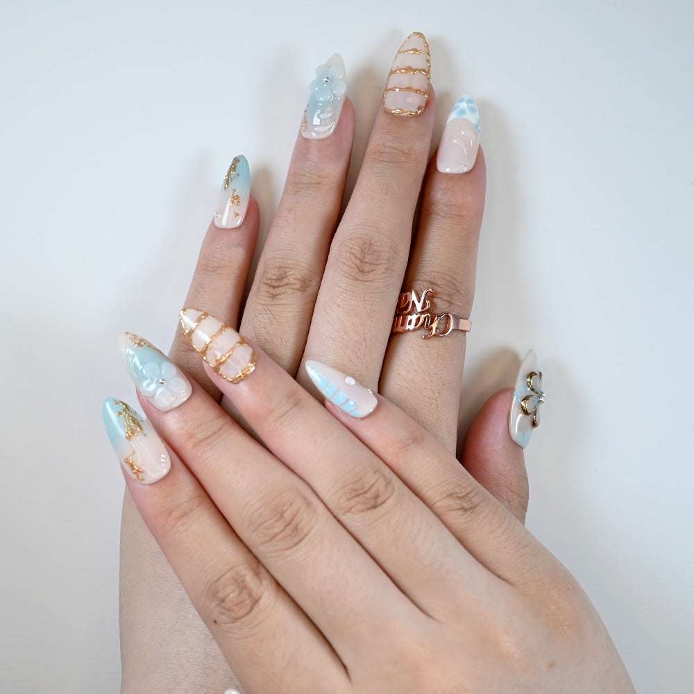 Medium almond reusable press-on nails with pastel blue accents and floral details