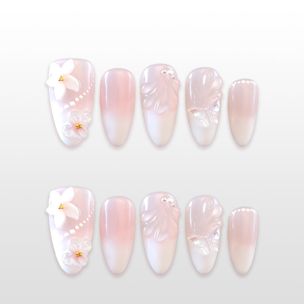 Pink and white ombre press-on nails with 3D flowers, pearls, and butterfly details