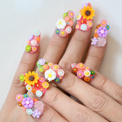 Bright pink press-on nails with 3D flowers, greenery, and sparkling accents