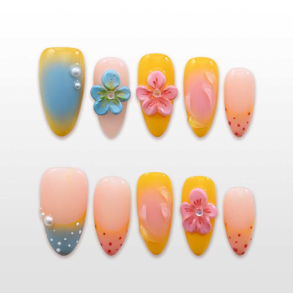 Yellow and pink press-on nails with 3D flowers, pearl accents, and gradient design