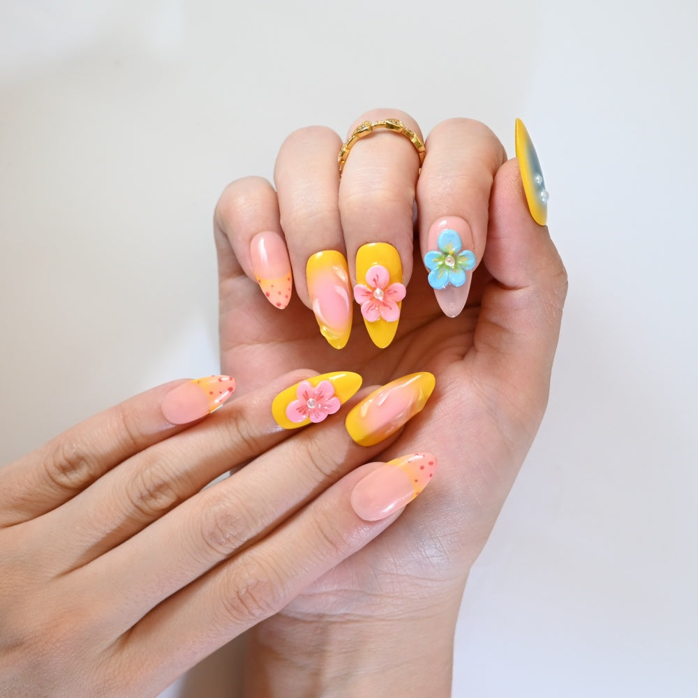 Candy-colored press-on nails with blue, pink, and yellow tones plus floral embellishments