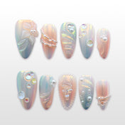 Iridescent press-on nails with 3D floral accents, pearl chains, and crystal bubbles