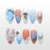 Romantic press-on nails with pastel blue and peach gradient, silver bow charms, and floral accents