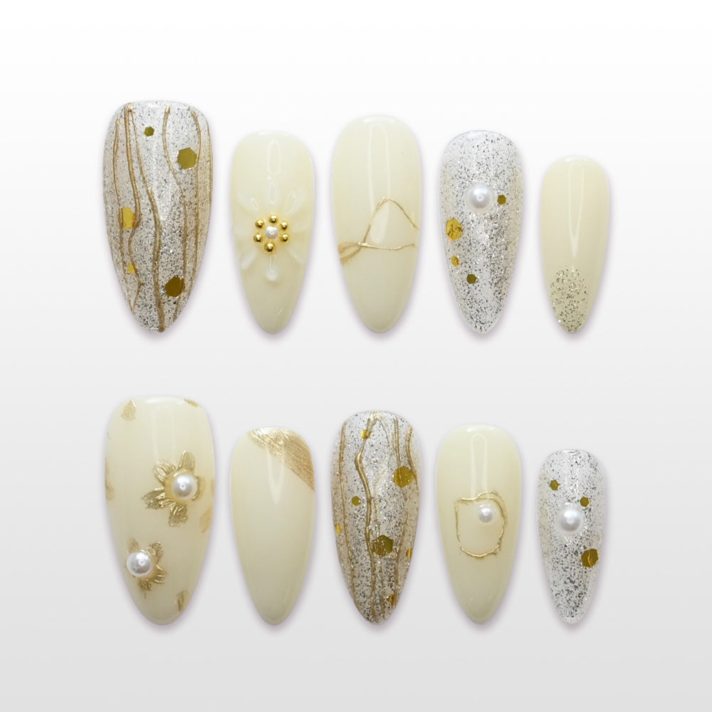 Elegant gold and silver glitter press-on nails with pearl accents and abstract metallic lines