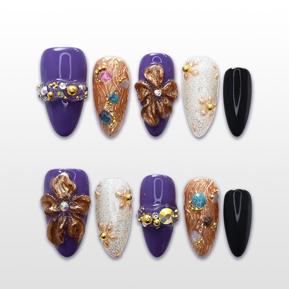 Purple press-on nails with bronze 3D flowers, gemstone accents, and gold glitter details