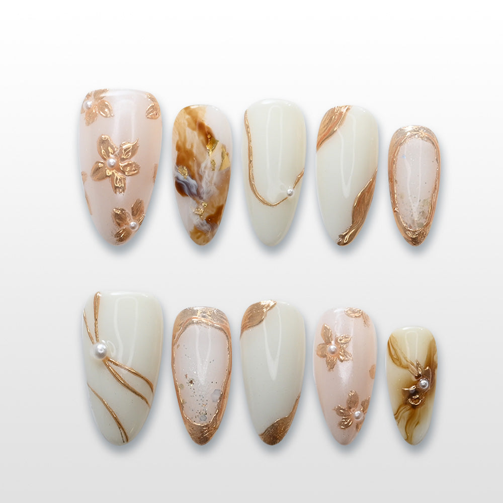 White and gold press-on nails with marble accents, 3D pearl details, and floral patterns