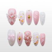 Pink press-on nails with 3D floral designs, pearl accents, and gold star embellishments