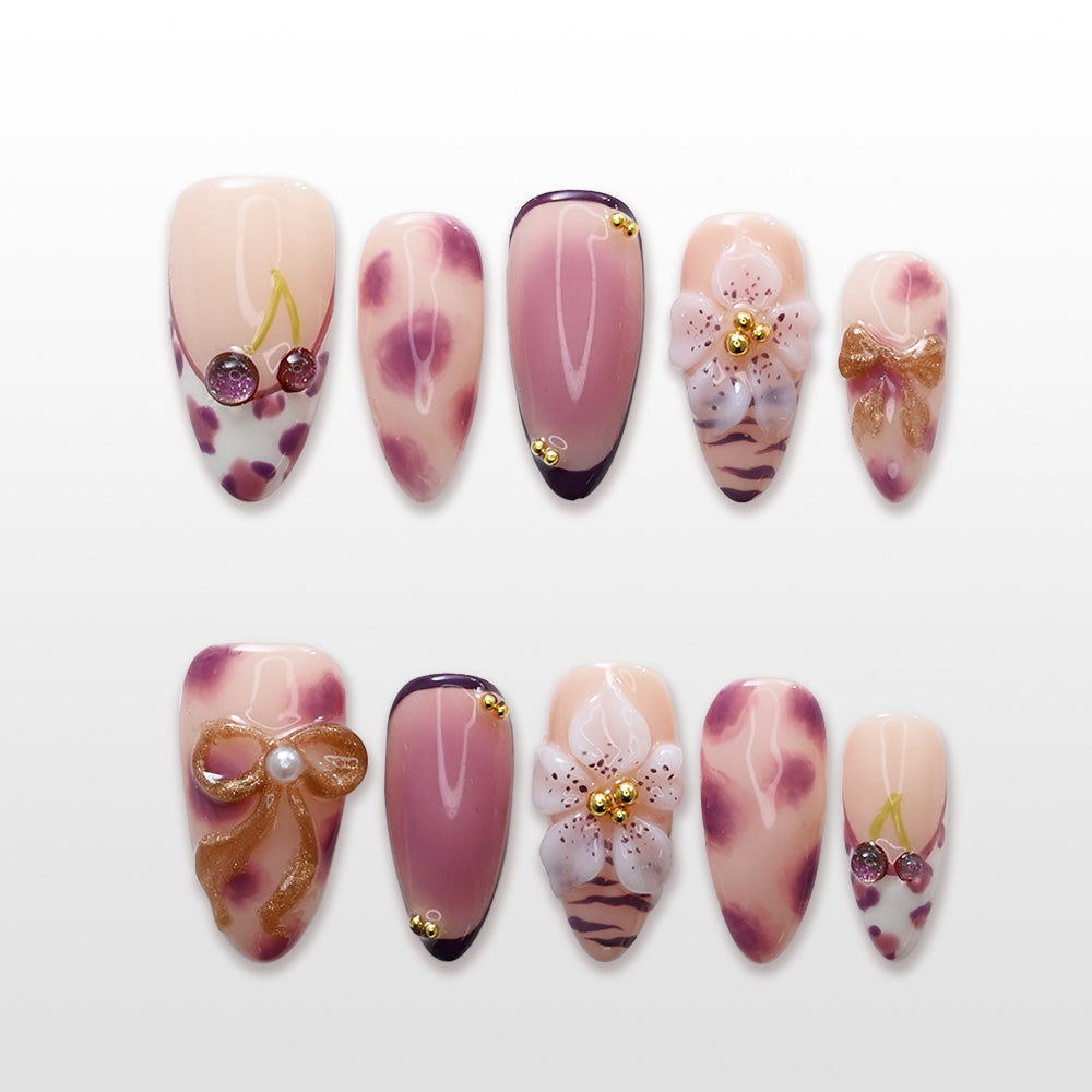 Pink and nude press-on nails with cherry charm, leopard print, and 3D gold bow design