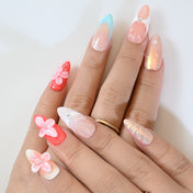 Spring floral press-on nails with mixed designs, turquoise tips, and pink petal embellishments